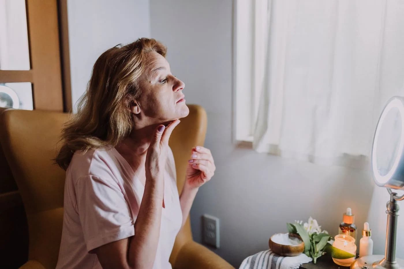 Mature woman examining the firmness of her jawline and chin in the mirror